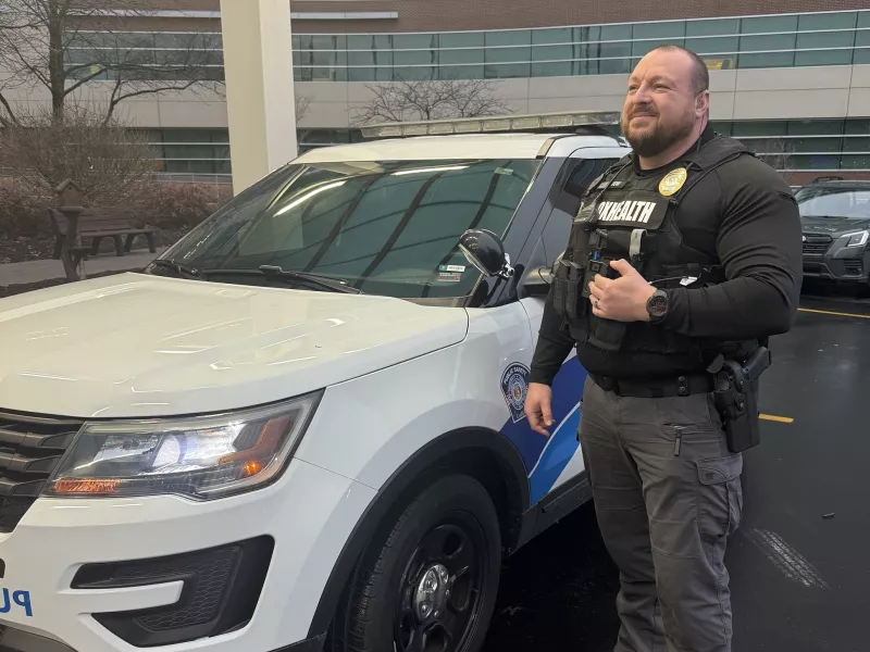 Security officer standing beside cruiser in front of hospital wearing body worn camera