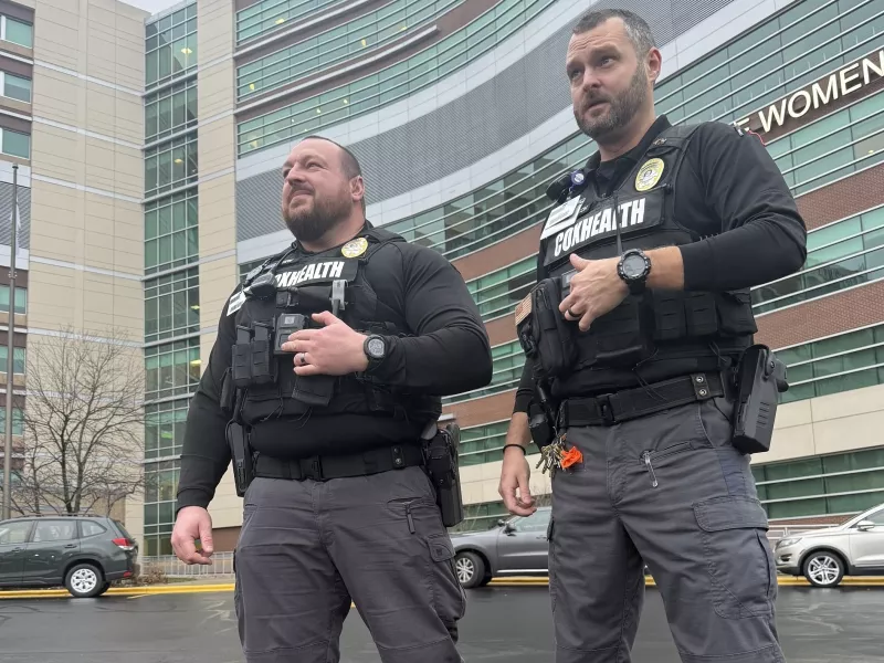 Two security officers wearing body cameras standing outside hospital
