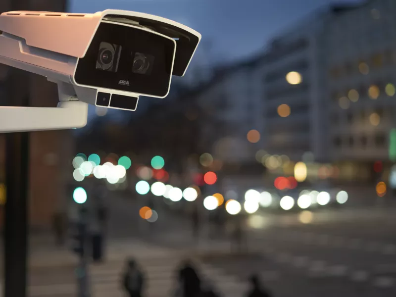 Box camera mounted on pole at night with blurred background