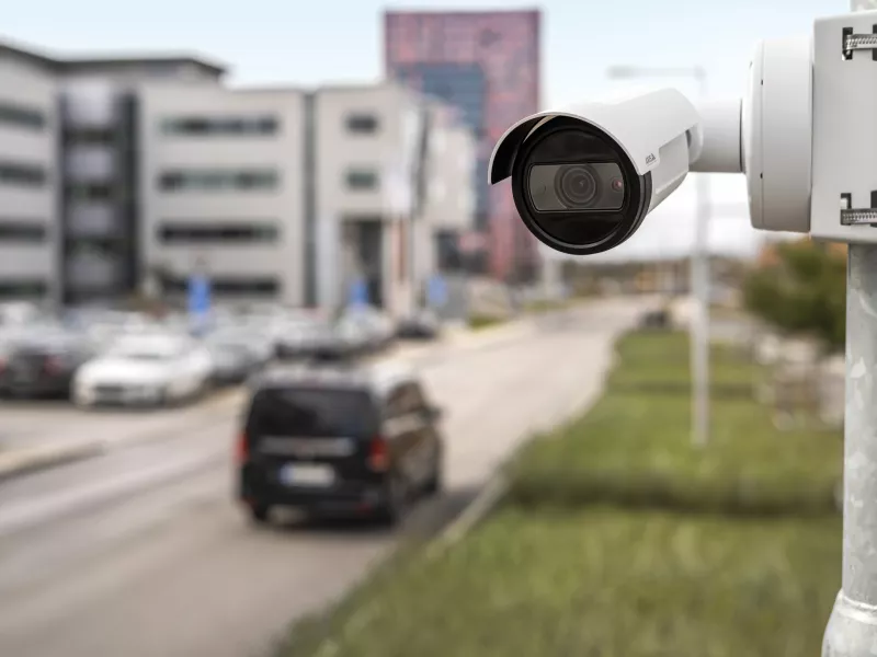 Bullet camera mounted on pole with car in blurred background