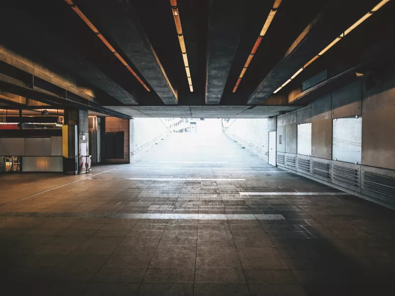 Large empty underground tunnel with bright light from the outside up ahead.