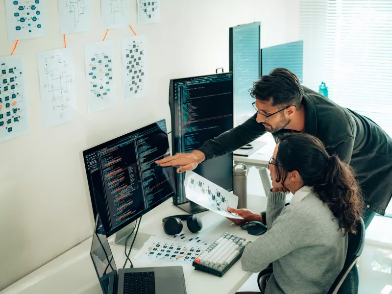 Programmers collaborating with the help of an office computer.