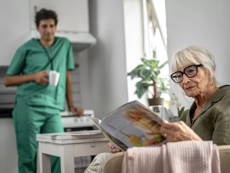 Elderly woman reading a magazine at home