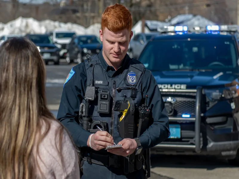 Officer with citizen and car in background