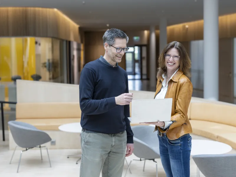 Carl Trotzig and Jeanette Skjelmose are looking at a computer and smiling