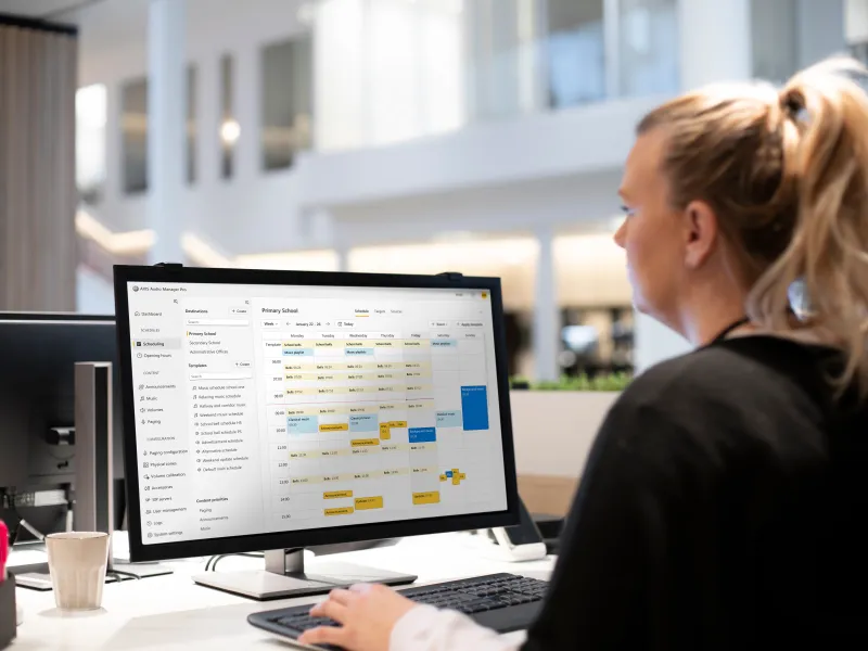 Woman using AXIS Audio Manager Pro and viewing a complex schedule on her computer screen 