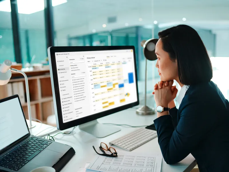 Woman using AXIS Audio Manager Pro C7110 and viewing a complex schedule on her computer screen 