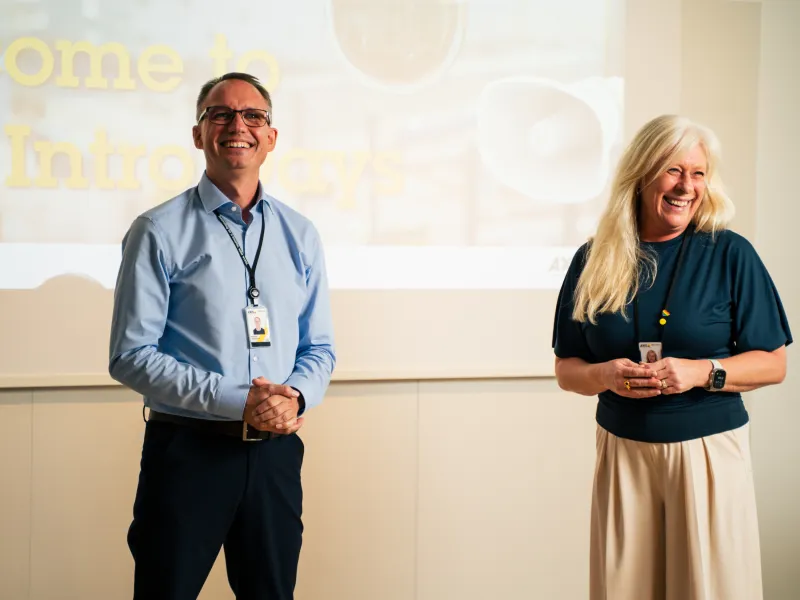 Martin Andersen and Malin Svensson smiling, while holding a presentation