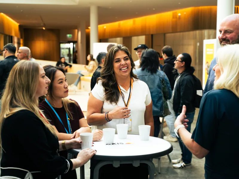 Axis employees smiling, while standing and talking around a small table