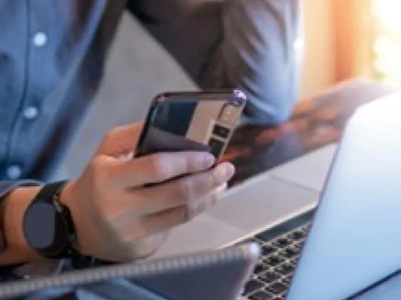 Man holding phone by a laptop