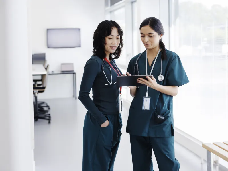 two Asian female medical professionals reviewing information on a tablet