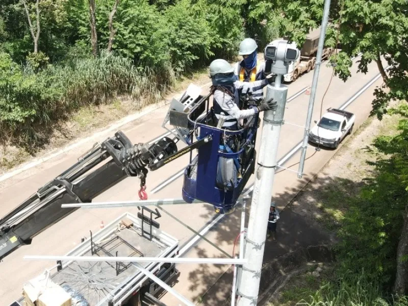 Two men in bucket raised above roadway working on cameras