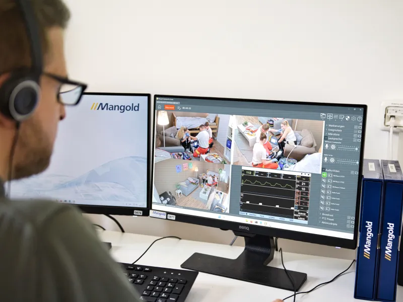 A professional monitoring a medical training simulation using a computer and tablet.