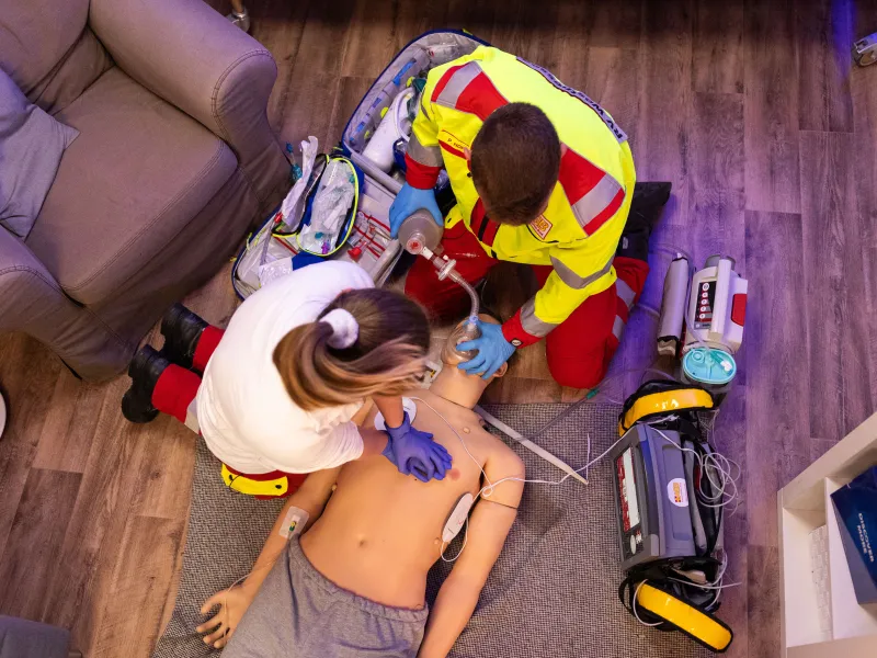 Two emergency responders performing CPR and ventilation on a medical training mannequin.