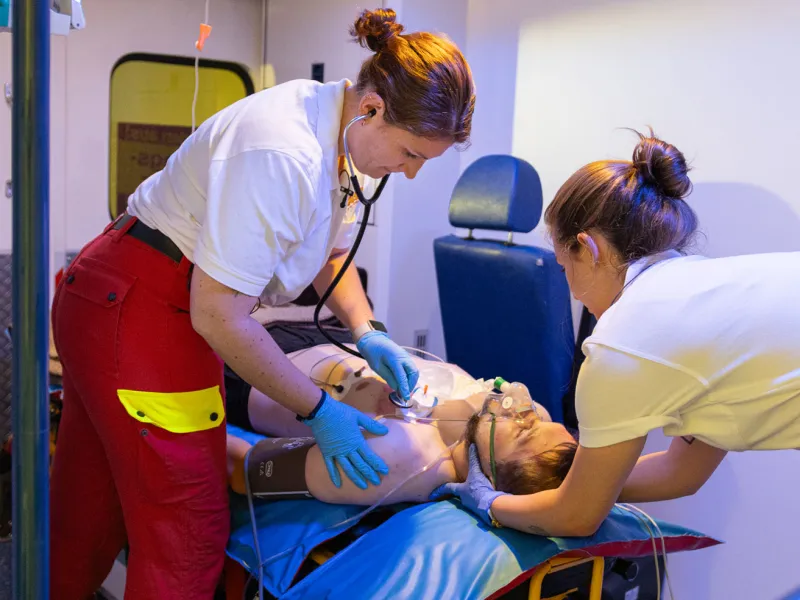 Paramedics providing medical care to a patient on a stretcher inside an ambulance.