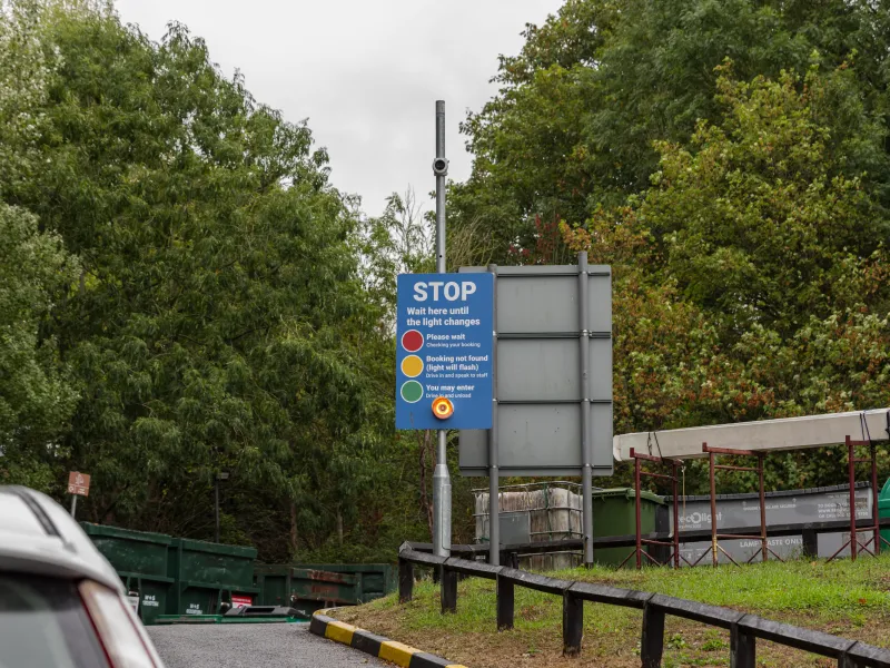 Stop sign explaining the traffic-light booking system at a Dorset recycling centre entrance