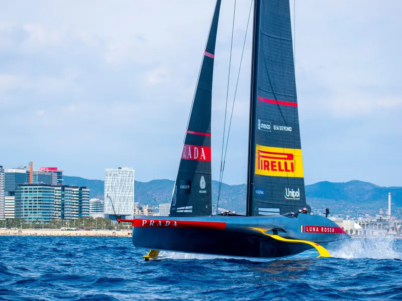 Luna Rossa Prada Pirelli sailboat racing near Barcelona's coastline during the America's Cup