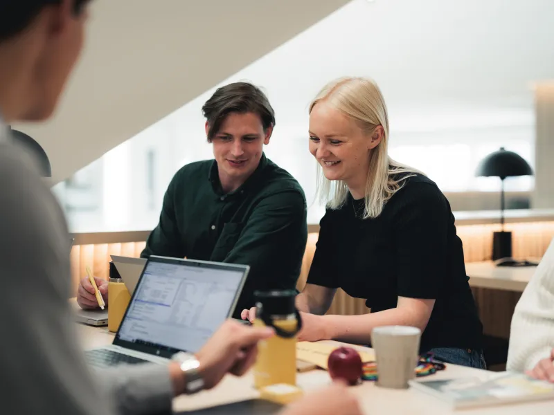 A group of Axis student workers collaborating around a table in a bright workspace.