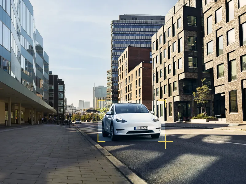 Car driving in city with high buildings around the car 
