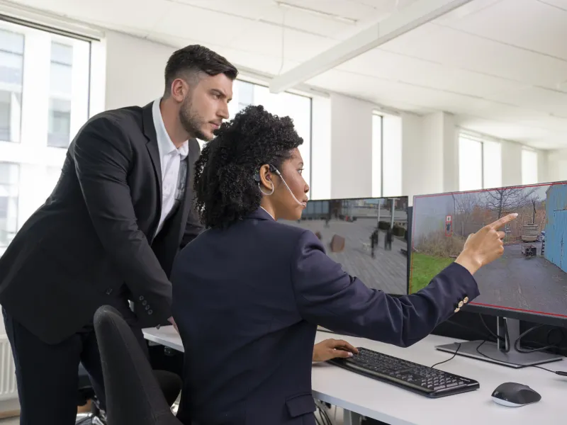 Two security guards watching surveillance footage with the help of AXIS Analytics used in cameras.