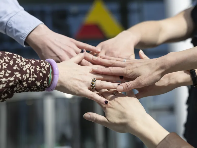 Hands of Axis colleagues grouped together. Axis logo in the background.