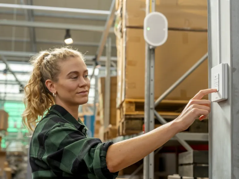 Woman in a warehouse pressing on a AXIS C8310 Volume Controller.