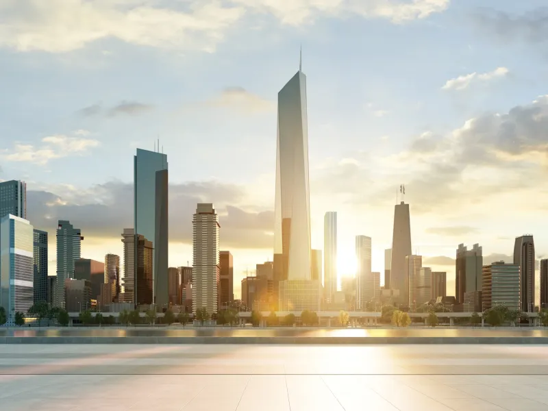 Modern city skyline with skyscraper buildings with a sunrise behind them. The city is surrounded by the ocean.