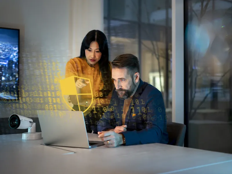 Cybersecurity woman and man sitting around laptop