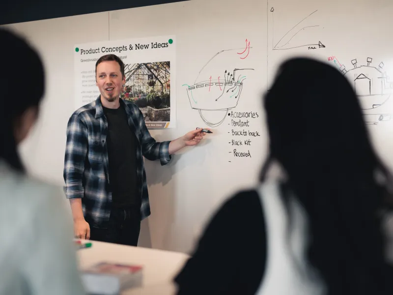 Axis employee standing in front of a whiteboard, presenting to a group in a conference room at Axis Communications.