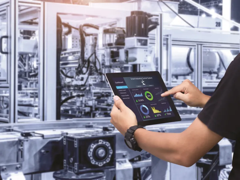 Man holding a tablet with information about the industrial machine in front of him.