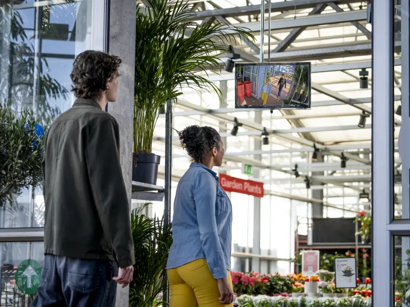 A man and a woman walking through a flower store entrance.