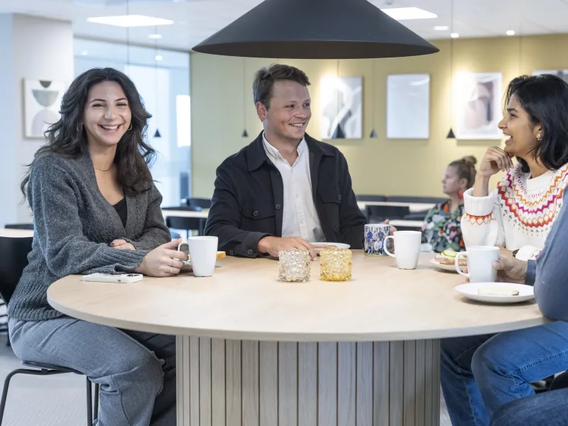 Colleagues having a coffee together, smiling and laughing.