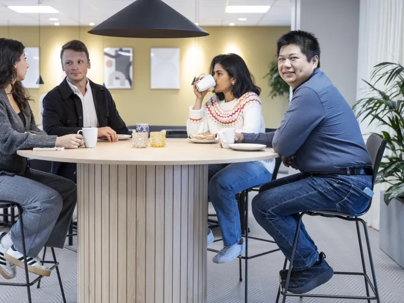 Axis colleagues sitting around a round table, having a relaxed conversation.