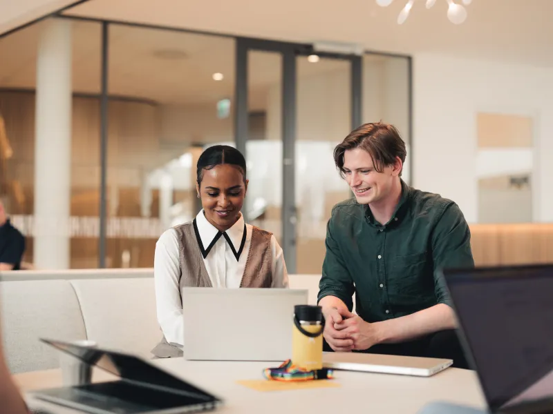 Two Axis colleagues sitting next to each other, looking jointly at a laptop screen.