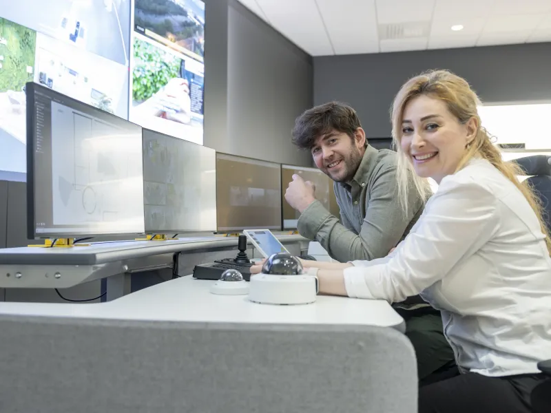 Two Axis software engineers monitoring multiple screens in a control room.