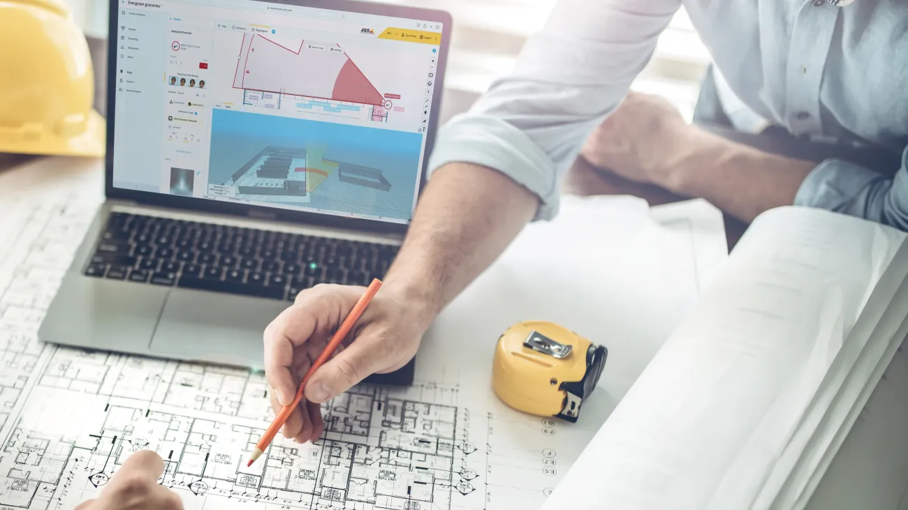 People discussing over architecture drawings with a laptop beside them.