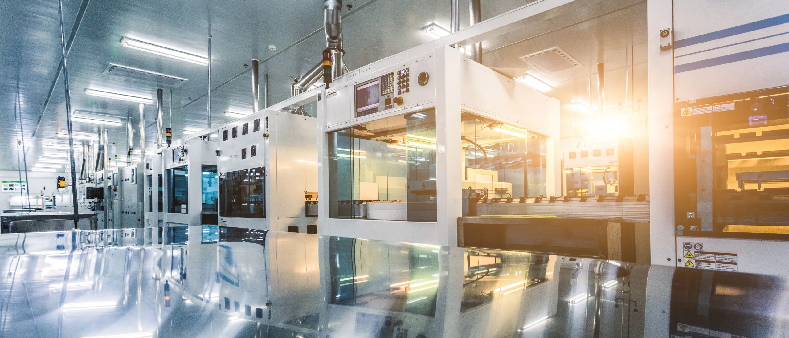 Modern, clean industrial facility with white machines, glass panels, reflective floor. Bright lights, sun flare.