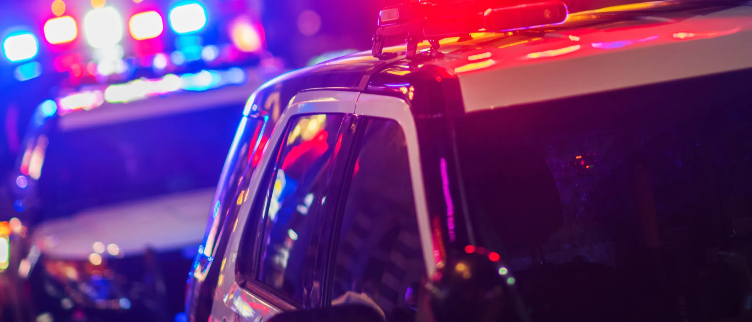 Close-up of police vehicles with red and blue emergency lights illuminated during a nighttime response.