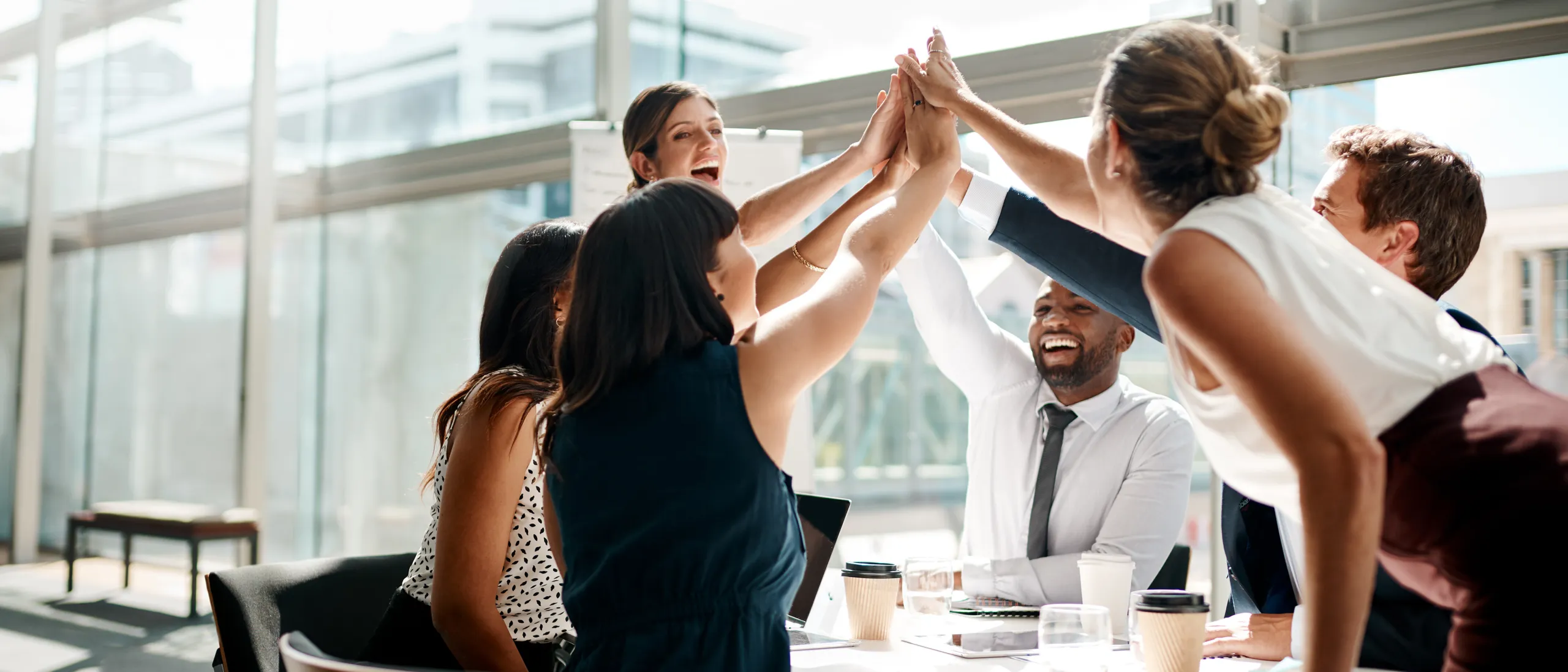 Work colleagues high fiving in a meeting.