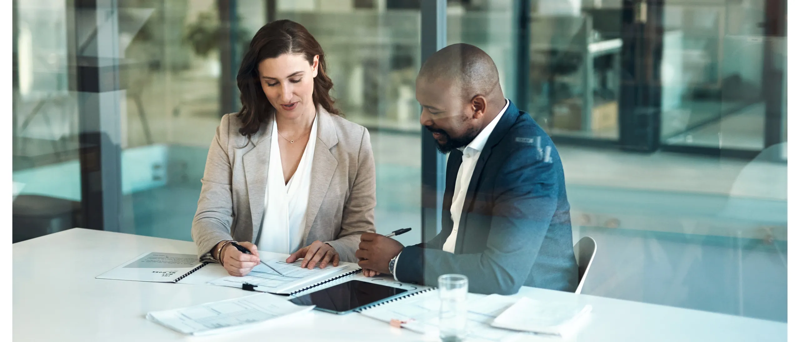 two people sitting and talking while papers lying on the table.