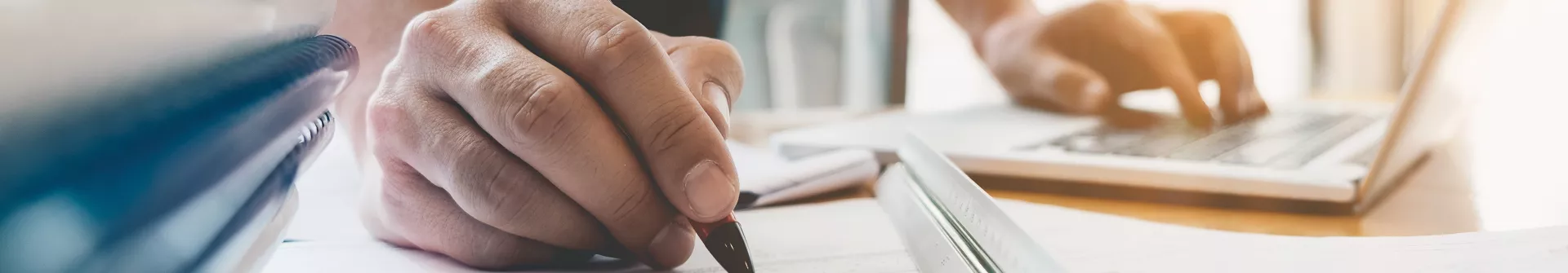 A hand with a pen, writing on a piece of paper