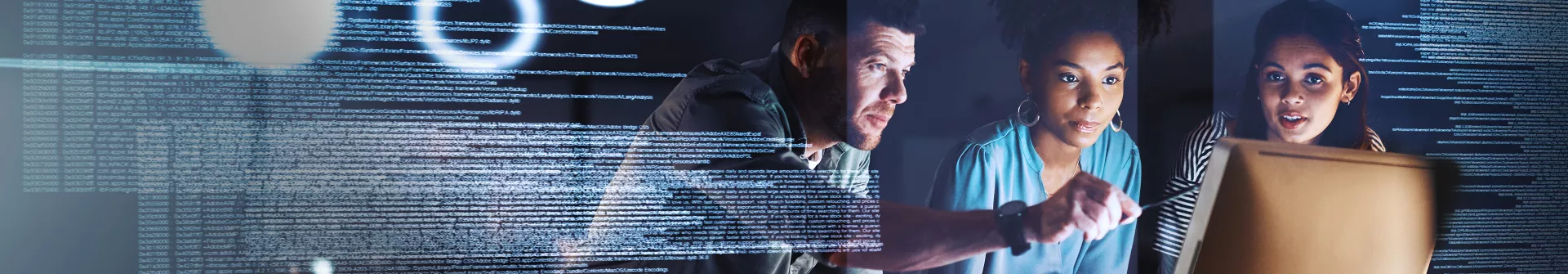 programmers standing infront of a desktop screen, discussing
