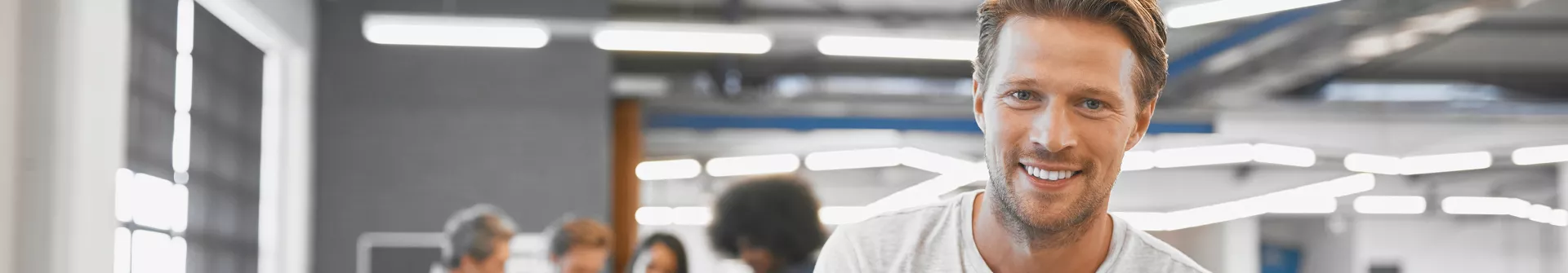 Smiliag man sitting on a table with crossed arms.
