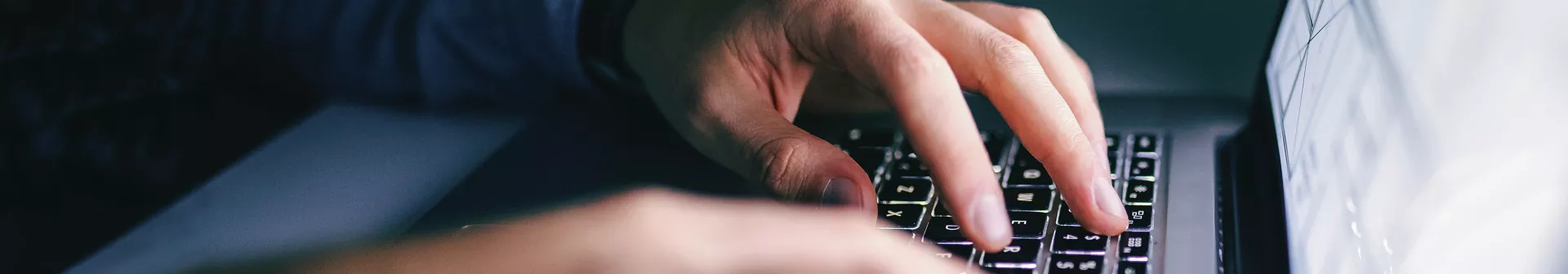 Hands typing on laptop keyboard