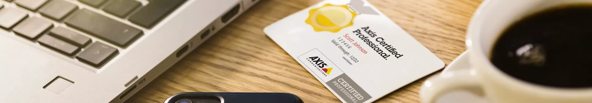 Certification card next to a computer and cup of coffee