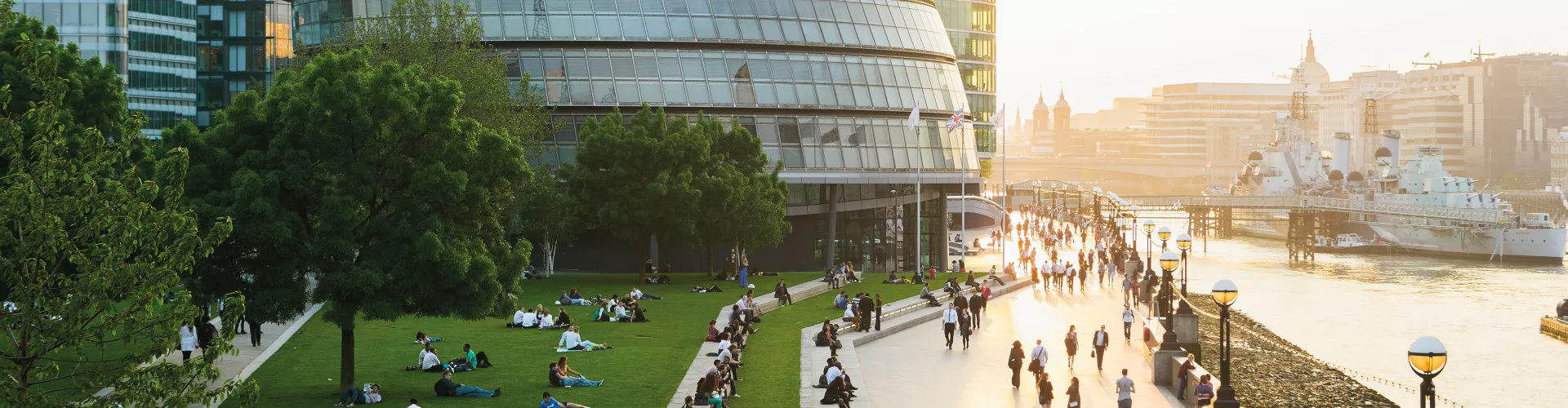 Sunset in a city with a building and people passing by 