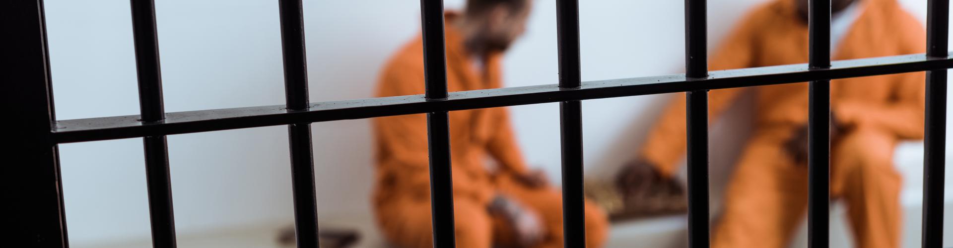 Prisoners in orange jumpsuit playing a game behind bars