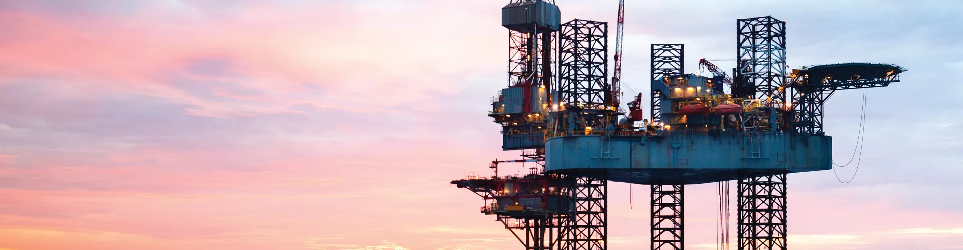 Oil rig in ocean during sunset