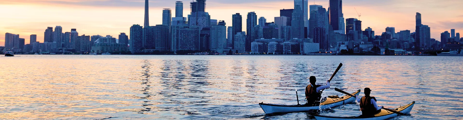 Two people are paddling in kayaks in the city skyline