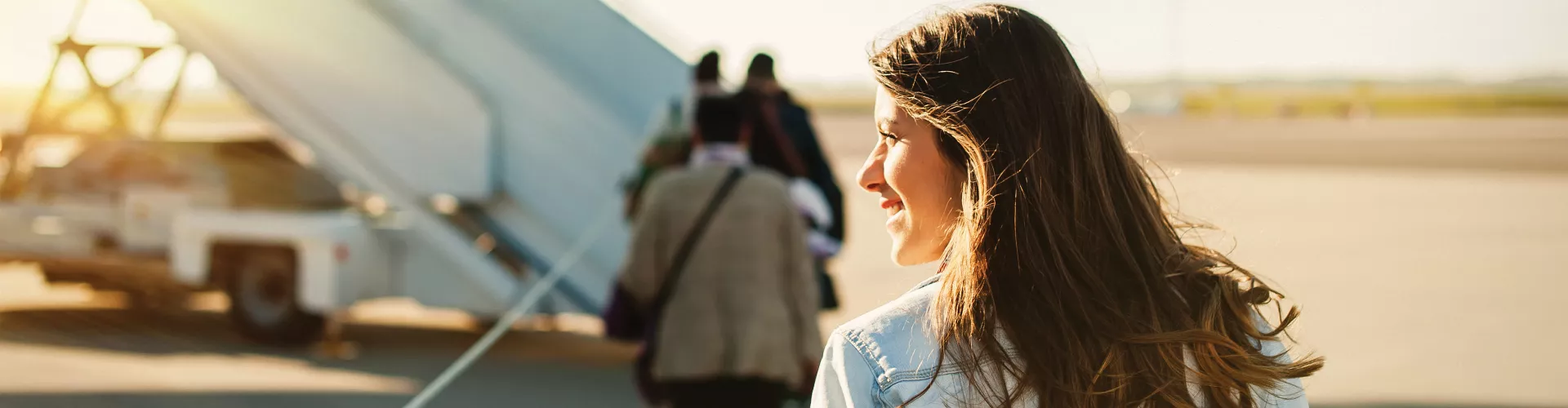 Woman boarding airplane with sunlight in the background